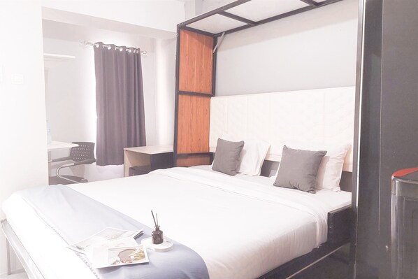 A modern hotel room with a large bed, a wooden accent wall, and a separate bathroom area. - Brand New Studio Apartment At Urbantown Serpong (South Tangerang)