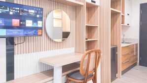 A modern room with a wooden desk, a chair, a TV mounted on the wall, and built-in shelving.