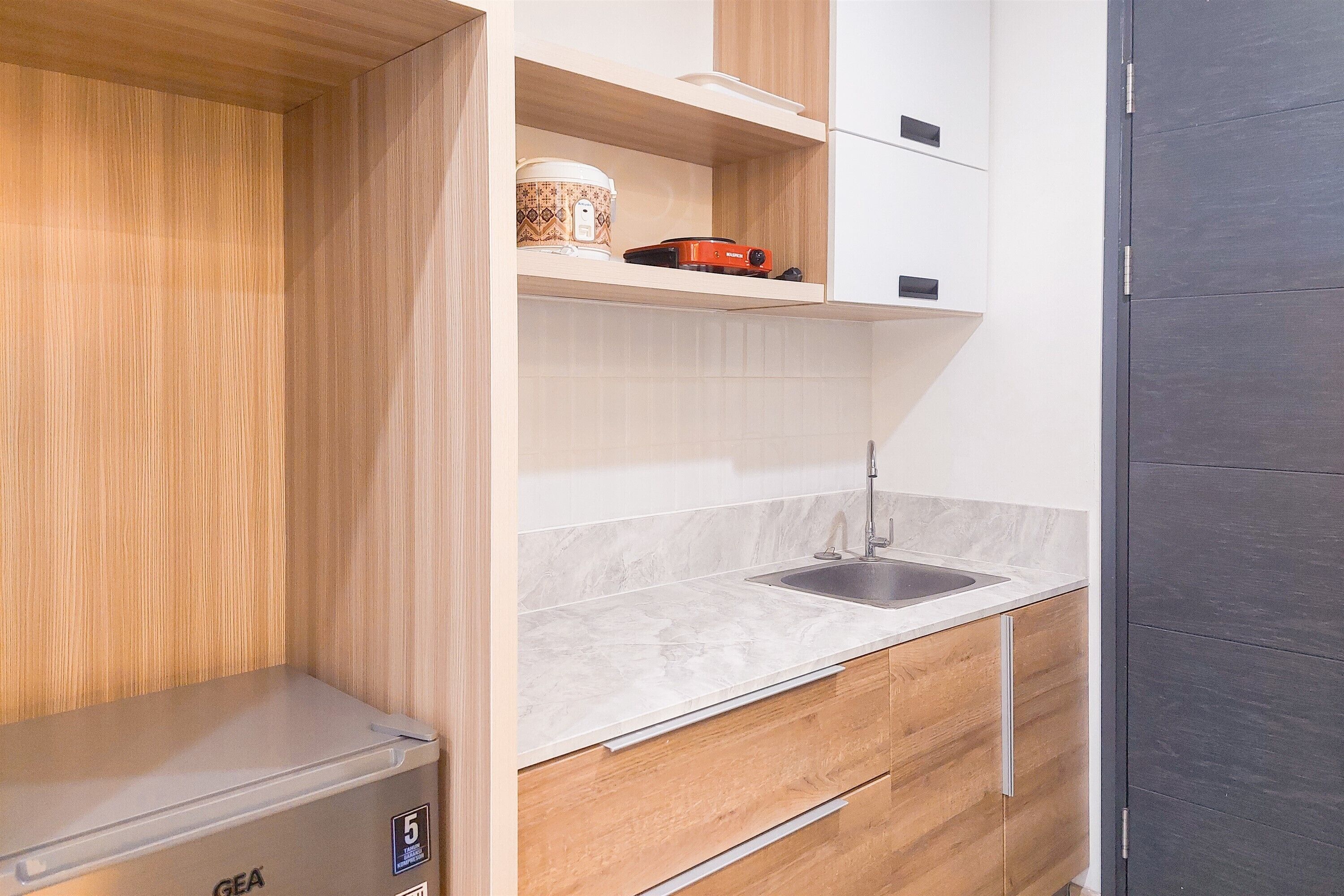 A compact kitchen with a sink, wooden cabinets, and a GEA appliance.