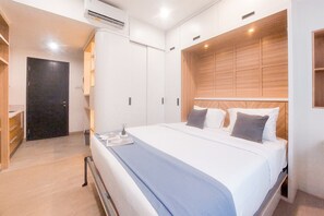 A hotel room with a large bed, a wardrobe, and a door. - Good Choice And Homey Studio Apartment At Collins Boulevard (Tangerang)