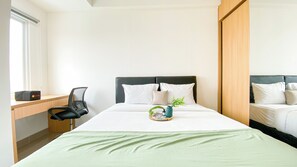 A hotel room with a bed, a desk, and a chair. - Simply And Nice Studio Apartment B Residence (Pagedangan)