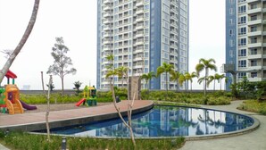 A residential area with a swimming pool, playground, and tall apartment buildings.