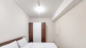 A hotel room with a bed, a wardrobe, and a door.