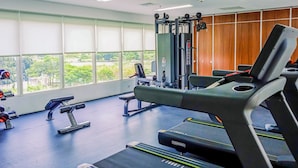 A gym with exercise equipment, large windows, and a view of greenery.