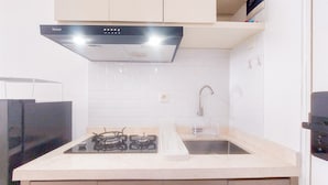 A kitchen with a gas stove, a sink, and a stainless steel faucet. - Best Deal Studio Apartment Urbantown Serpong (South Tangerang)