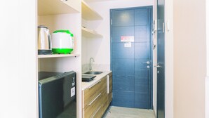 A compact kitchen with a refrigerator, a sink, and a microwave. - Comfort And Cozy Stay Studio Collins Boulevard Apartment (Tangerang)