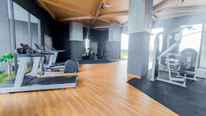 A gym with treadmills, a weight machine, and a mirrored wall. - Comfort And Cozy Stay Studio Collins Boulevard Apartment (Tangerang)