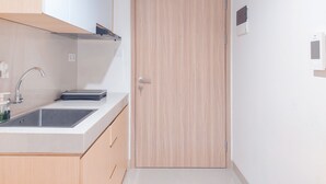 A modern kitchen with a sink, cabinets, and a wooden door. - Modern Look 1Br Without Living Room At Bintaro Embarcadero Apartment (South Tangerang)