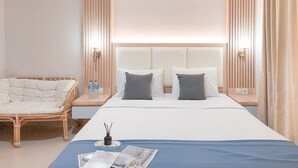 A hotel room with a large bed, two bedside tables, a wicker chair, and a nightstand with a lamp. - Modern Look 1Br Without Living Room At Bintaro Embarcadero Apartment (South Tangerang)
