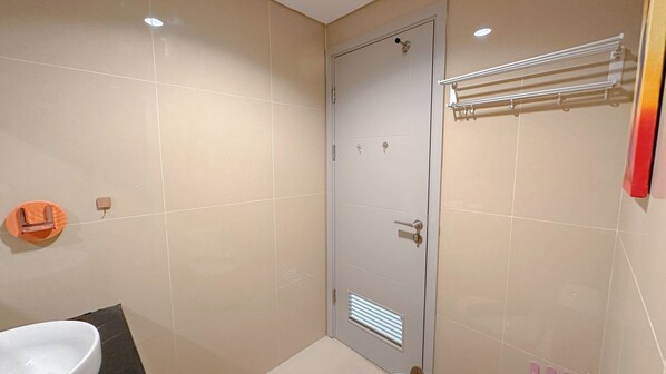 Un baño con puerta blanca, toallero y lavabo.
