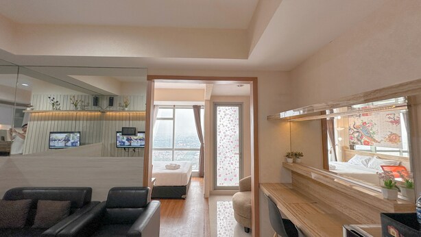 A modern hotel room with a large bed, a desk, a chair, a TV, and a view of the city through the window.