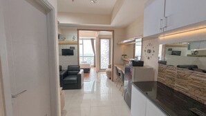 A modern kitchen with a built-in oven, a dining area with a table and chairs, and a living room with a sofa and a TV.