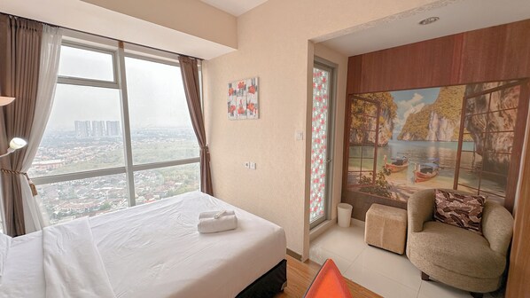 Habitación de hotel con una cama grande, una silla, vista a la ciudad y un mural en la pared.