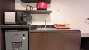 Une cuisine compacte équipée d’un réfrigérateur GEA, d’un four à micro-ondes, d’un évier et d’un égouttoir à vaisselle.