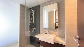 Une salle de bain moderne avec une douche à parois de verre, un lavabo blanc et un grand miroir.