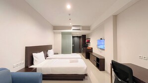 Une chambre d’hôtel avec deux lits, un bureau, une chaise, une télévision et une armoire.