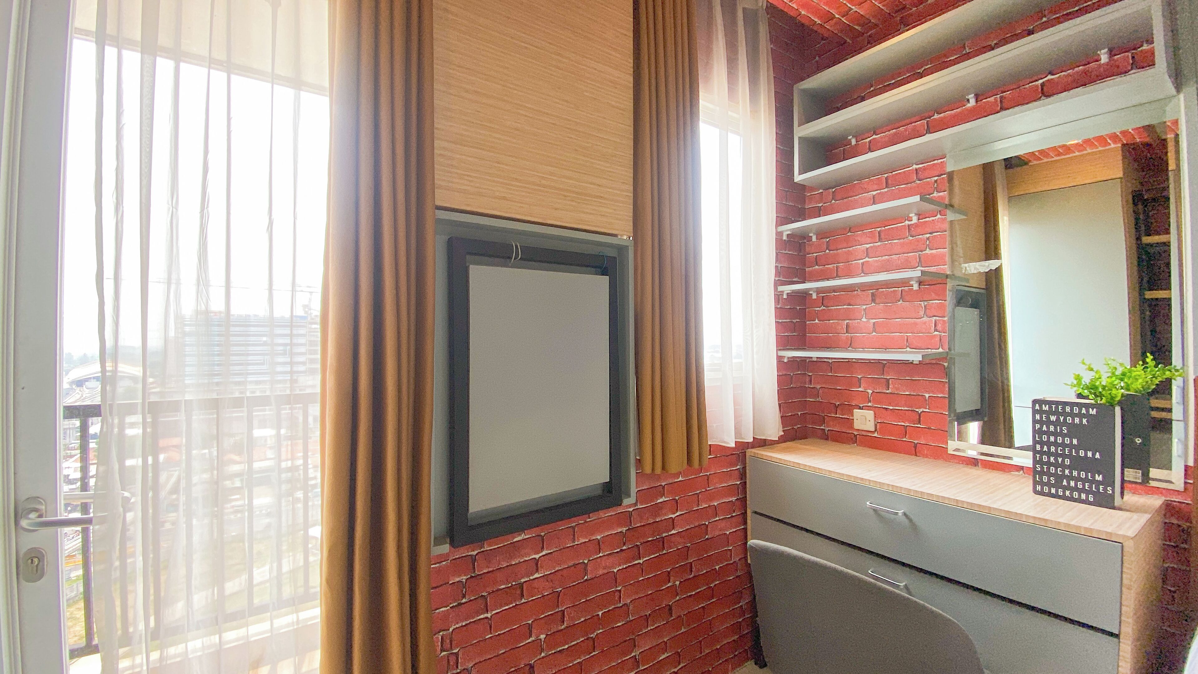 A room with a brick wall, a wooden cabinet, a mirror, and a window with curtains.