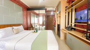 A hotel room with a bed, a TV, a wardrobe, and a mirror. - Strategic And Comfy Studio Apartment At Signature Park Grande (Jakarta)