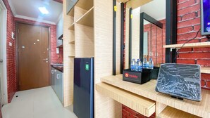 A hotel room with a wooden counter, a refrigerator, a water dispenser, and a television. - Strategic And Comfy Studio Apartment At Signature Park Grande (Jakarta)