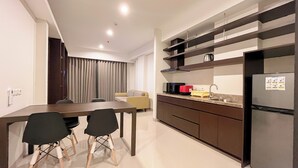 A modern kitchen with a dining area, including a table and chairs, a sofa, and a refrigerator. - Modern And Stylish 2Br (No Kitchen) Apartment At Skales Residence Nusa Dua Bali (Nusa Dua)