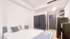 Una camera d'albergo con un letto, un armadio, una scrivania e un frigorifero.