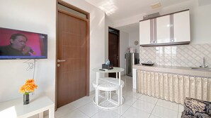 A modern living room with a TV, a small table, and a sofa. - The Elevated Abode 2Br At Mekarwangi Square Cibaduyut Apartment (Bandung)