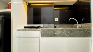 A kitchen with a granite countertop, a sink, and a dishwasher. - Best Value Studio Room Transpark Cibubur Apartment (Depok)