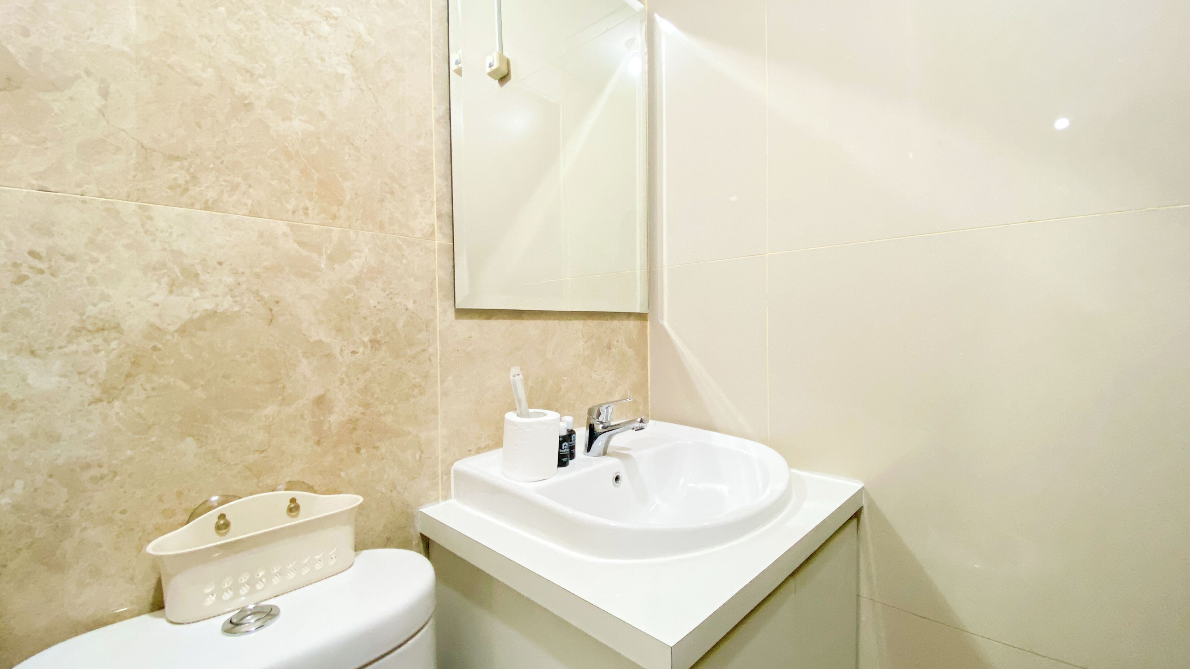 A bathroom with a white sink, a mirror, and a toilet.