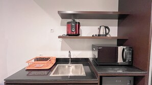 Une cuisine compacte équipée d’un évier, d’un four à micro-ondes, d’une machine à café et d’un égouttoir à vaisselle.
