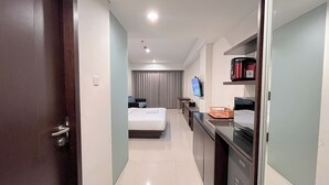 A hotel room with a bed, a desk, a television, and a minibar. - Stylish Studio (No Kitchen) Apartment At Skales Residence Nusa Dua Bali (Nusa Dua)