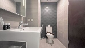A modern bathroom with a white sink, chrome faucet, and a toilet with a wooden seat. - Stylish Studio (No Kitchen) Apartment At Skales Residence Nusa Dua Bali (Nusa Dua)
