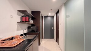Une cuisine moderne avec un plan de travail noir, un évier et un plateau en bois. Une porte donne accès à une autre pièce.