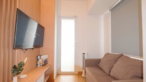Un salon moderne avec un téléviseur à écran plat fixé à un mur en bois, un canapé, une petite table avec une plante et un radiateur.