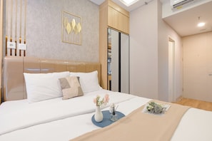 A modern hotel room with a large bed, a wardrobe, and a decorative wall piece.