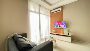 A modern living room with a sofa, a coffee table, and a TV mounted on a wooden panel wall.