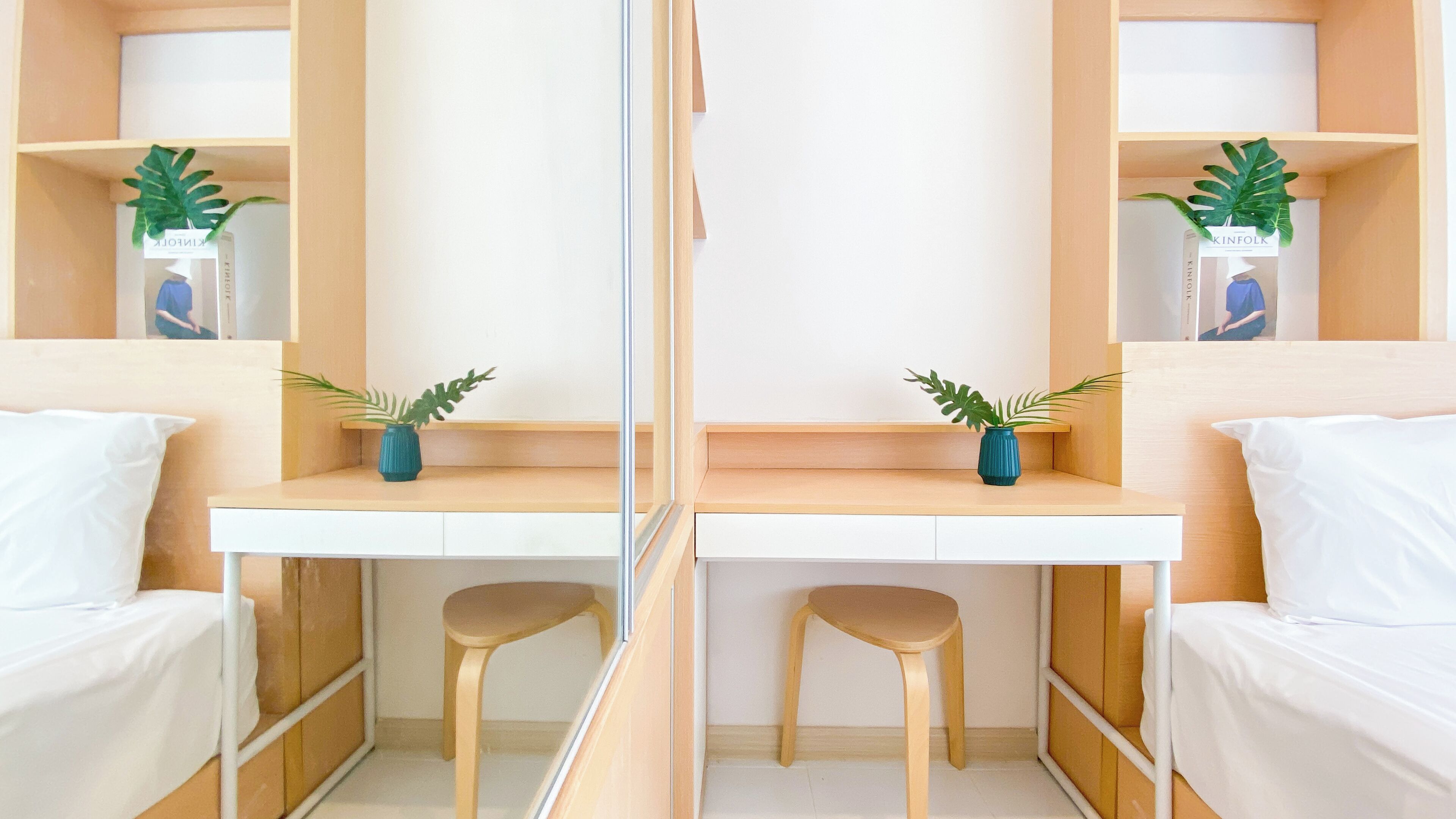 A mirrored room with a white desk, two stools, and two shelves with plants.
