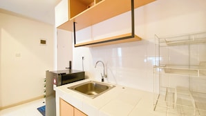 A modern kitchen with a stainless steel sink, white cabinets, and a built-in shelf unit. - Comfortable And Simply 2Br At Tokyo Riverside Pik 2 Apartment (Teluknaga)