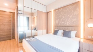 Ein modernes Hotelzimmer mit einem großen Bett, einem Kleiderschrank, einem Nachttisch und einer dekorativen Wandverkleidung.