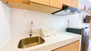 Cocina moderna con azulejos blancos, pileta de acero inoxidable, alacenas de madera y campana extractora negra.