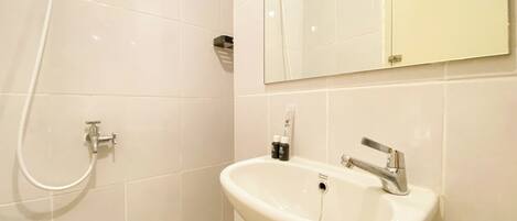 A bathroom with a white sink, a mirror, and a shower.