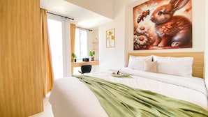 Une chambre d’hôtel avec un lit, un bureau, une chaise et un tableau représentant un lapin et une abeille.