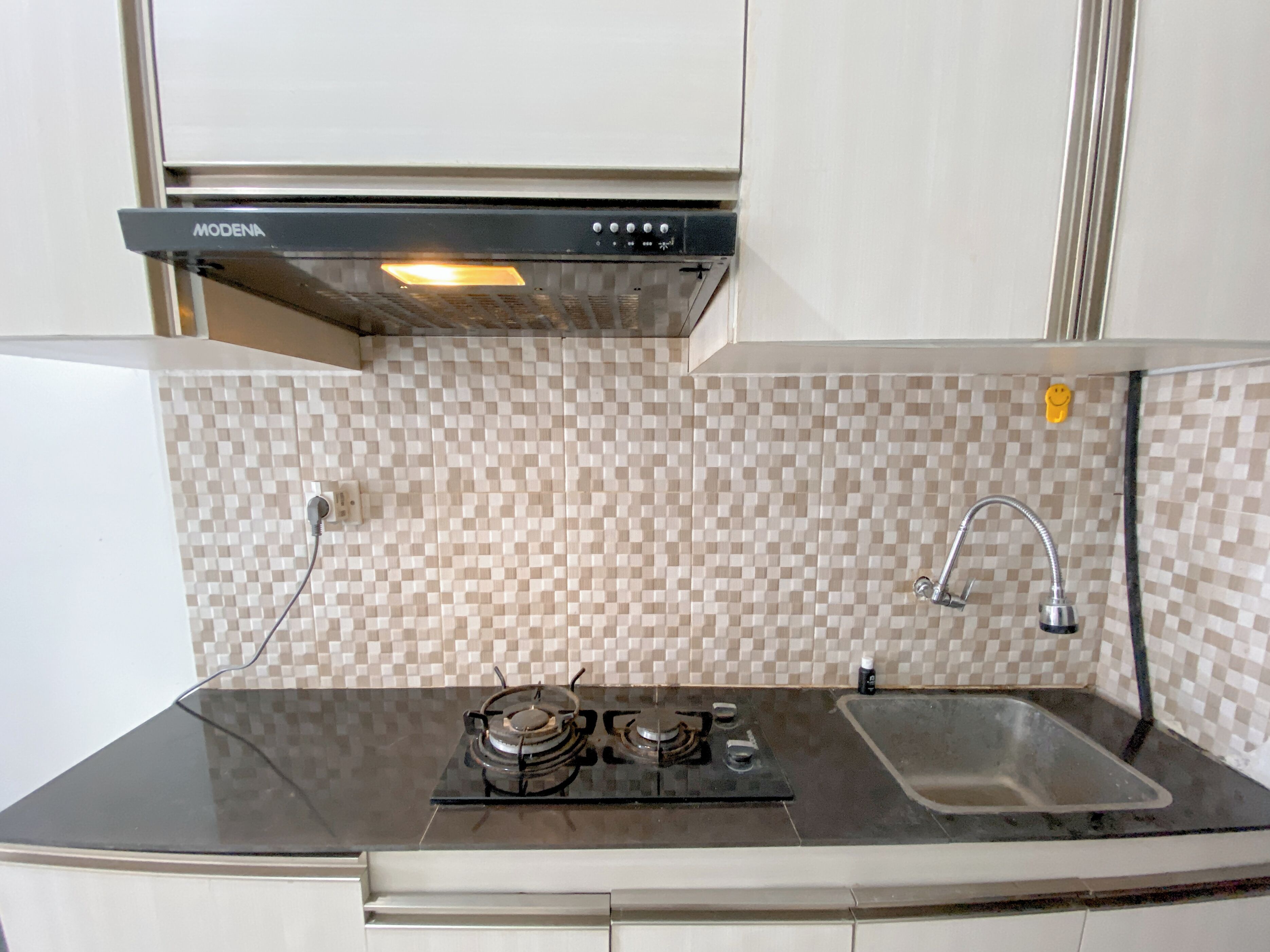 A kitchen with a gas stove, a sink, and a modern range hood.