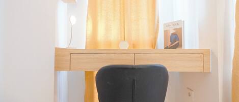 A study with a wooden desk, a black chair, and a book titled 'KINFOLK' on the desk.