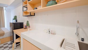 Una cucina moderna con ripiani in legno, piani di lavoro bianchi e un mobiletto nero.
