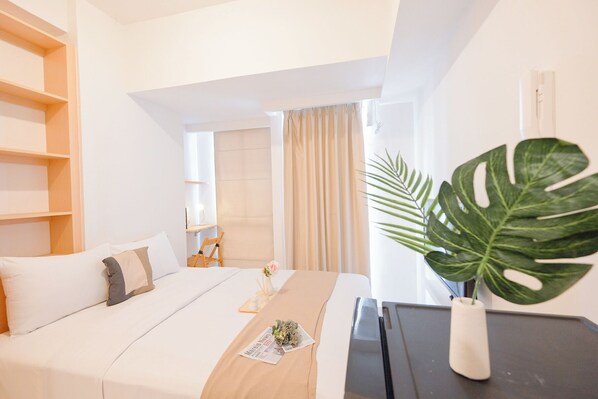 Relax in a serene space with a comfortable bed, a stylish nightstand, and a lush potted plant.