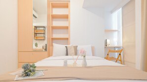 Una camera d'albergo moderna con un letto grande, un comodino in legno, una scrivania con una sedia e una parete attrezzata.