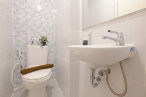 Bathroom features a toilet, sink, and mirror, with a towel and a small plant.