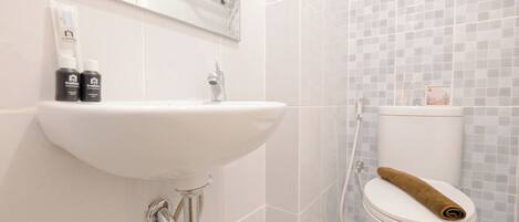 Ein Badezimmer mit einem weißen Waschbecken, einer Toilette mit Handtuch und einer Duschkabine.