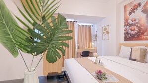 A hotel room with a bed, a desk, a chair, a large plant, and a painting on the wall. - Good Deal And Tranquil Studio Apartment Tokyo Riverside Pik 2 (Teluknaga)