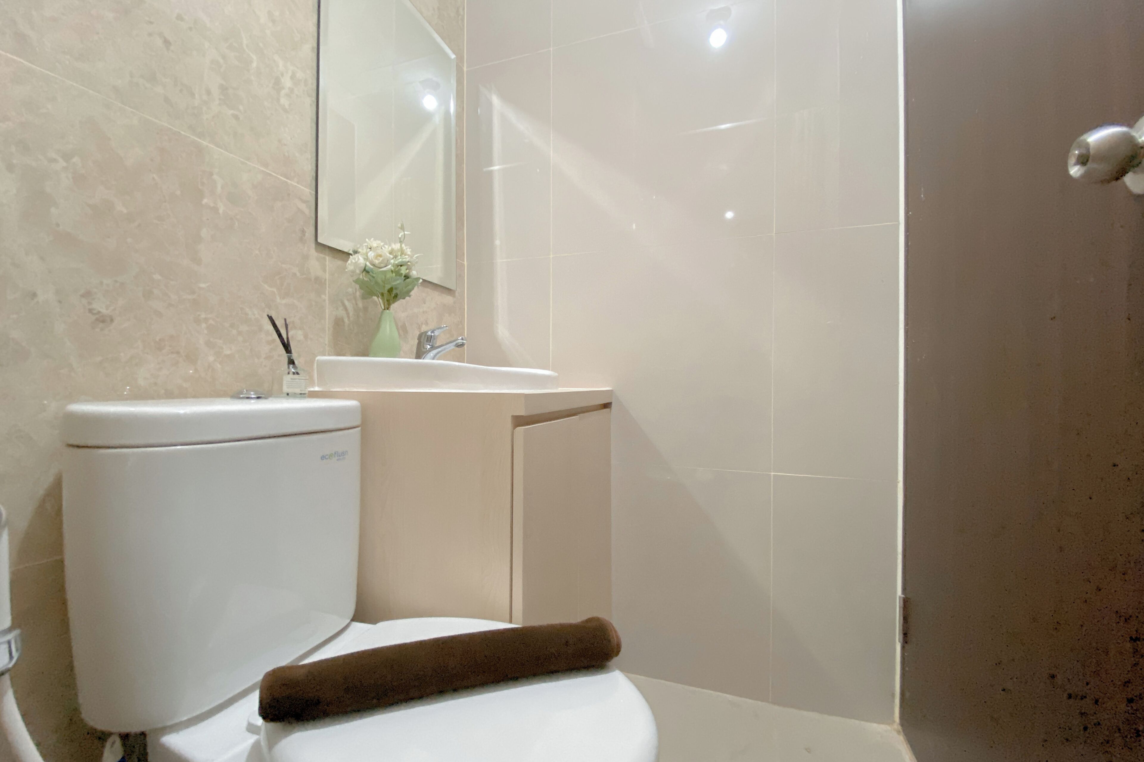 A bathroom with a toilet, sink, and mirror.